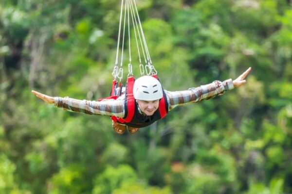 Person Zip Lining With Arms Out Stretched And A Big Smile